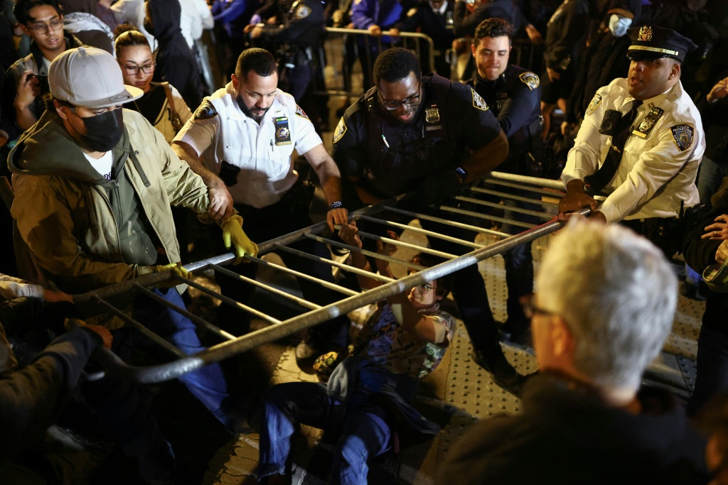 Protesters and law enforcement officers clash close to the scene where a man was shot by an ICE agent — CHARLY TRIBALLEAU / AFP