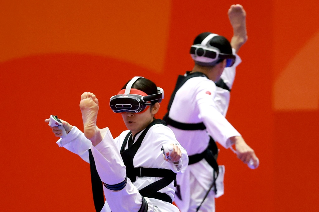 Japan’s Nakajima Miho (L) competes against compatriot Suzuki Hayate (R) in the mixed individual virtual taekwondo — DAVID GRAY / AFP