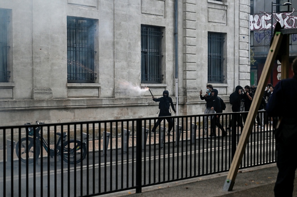 A protester holds a firework stick during protests in the soutwestern town of Bordeaux — Christophe ARCHAMBAULT / AFP