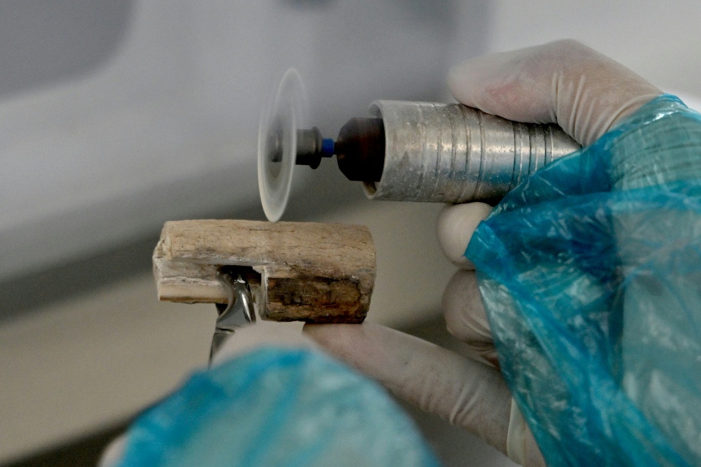 A staff member cuts a bone fragment from the remains of a fallen soldier at the Center for DNA Identification (CDI), which is part of the Vietnam Academy of Science and Technology, in Hanoi — Nhac NGUYEN / AFP