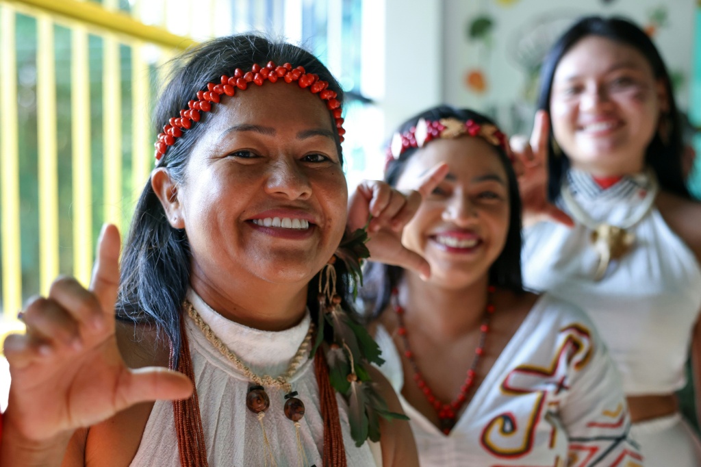 Indigenous Kambeba women supporting Brazil's President Luiz Inacio Lula da Silva make an 'L' gesture with their hands while queueing to vote during the presidential election — MICHAEL DANTAS / AFP