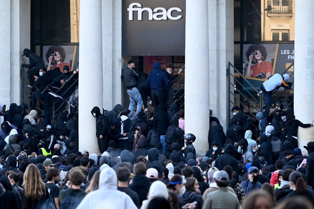 Looters climb over the gates of a consumer electronics store in the city of Nantes — Sebastien Salom-Gomis / AFP