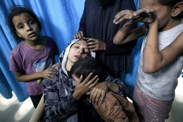 A wounded Palestinian woman from the Baraka family is surrounded by her children upon their arrival at Nasser Hospital in Khan Yunis in the southern Gaza Strip following Israeli air strikes that hit their building on November 13, 2023. 