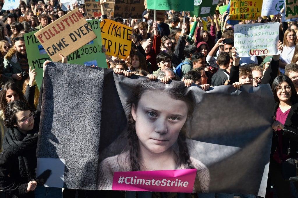 Pessoas e estudantes seguram cartazes e uma faixa mostrando a ativista política sueca Greta Thunberg, de 16 anos, em protesto contra o aquecimento global no centro de Roma, em 15 de março de 2019. Andreas SOLARO / AFP