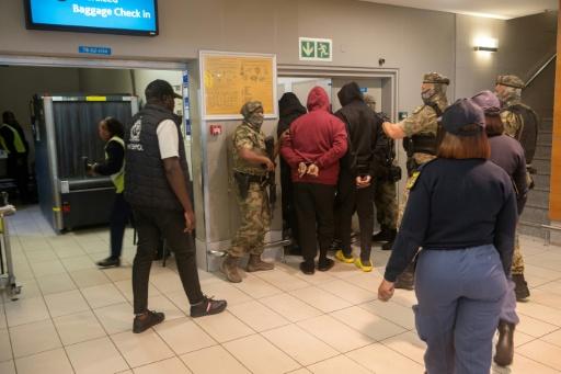 Six ressortissants nigérians sont escortés à l'aéroport du Cap, le 11 septembre 2026 en Afrique du sud, pour une extradition vers les États-Unis où ils répondront d'accusations d'arnagues à la romance — RODGER BOSCH / AFP