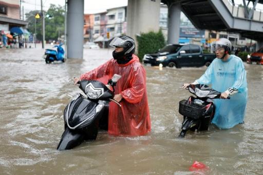 People push their motorcycles through floodwaters in the Bang Bua district of Bangkok on September 26, 2026. — WIKUS DE WET / AFP