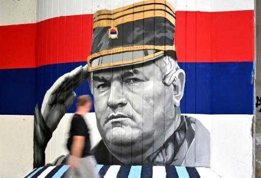 Un homme passe devant une fresque murale représentant l'ancien chef militaire des Serbes de Bosnie, Ratko Mladić, le 6 septembre 2026 à Belgrade, en Serbie, dont l'inhumation est prévue le 7 septembre 2026 au cimetière de Topčider à Belgrade, sur fond de critiques de l'UE concernant la "glorification" d'un criminel de guerre condamné pour génocide — OLIVER BUNIC / AFP