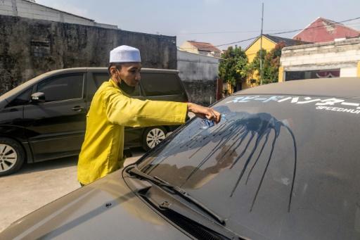 Un homme nettoie le pare-brise de sa voiture  couvert de cendre après l'éruption du volcan Anak Krakatoa à Bogor, dans la province de Java occidental, en Indonésie, le 6 septembre 2026 — ADITYA Aji / AFP