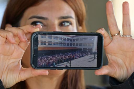 Principal May Mehdi shows a photograph of Burj Qalaway Intermediate School before it was damaged by Israeli strikes — Anwar AMRO / AFP