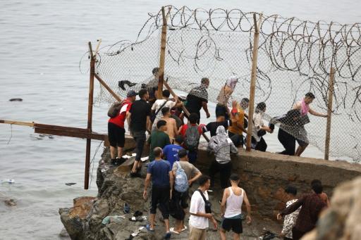 Unos migrantes atraviesan una valla en la zona fronteriza entre la localidad marroquí de Fnideq y la ciudad española de Ceuta, el 31 de julio de 2026 al norte de África — Abdel Majid Bziouat / AFP