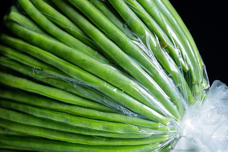 Cette photographie montre des haricots verts conditionnés dans un sachet en plastique.
